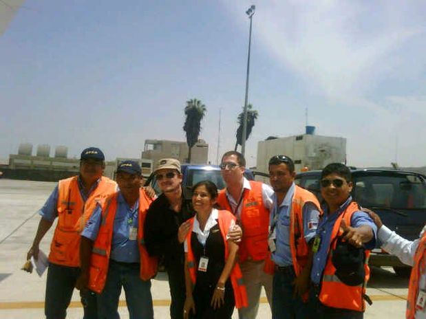 (Foto Radio Oxigeno) Bono posa al lado de un grupo de empleados aeroportuarios en Lima.